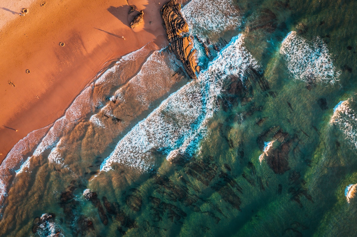 Luchtfoto van een zonnige kust als begin van een vliegvakantie
